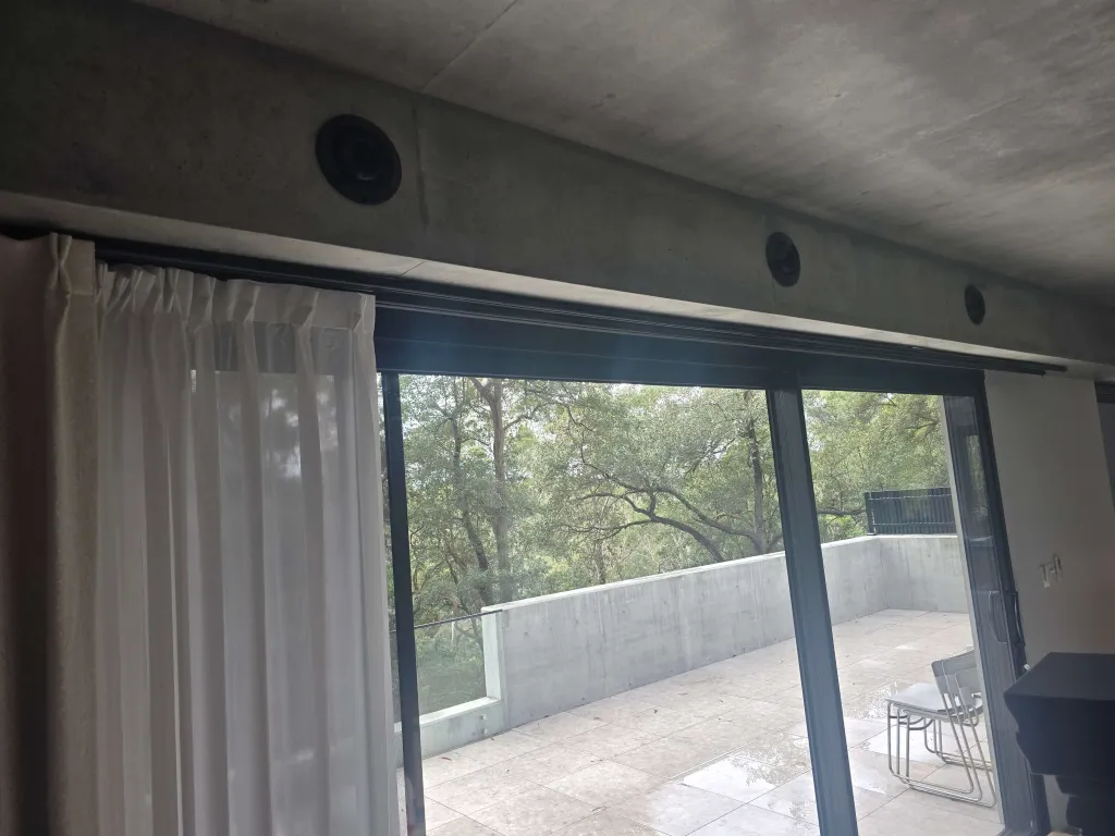Round ceiling supply diffusers above sliding glass doors in a living area