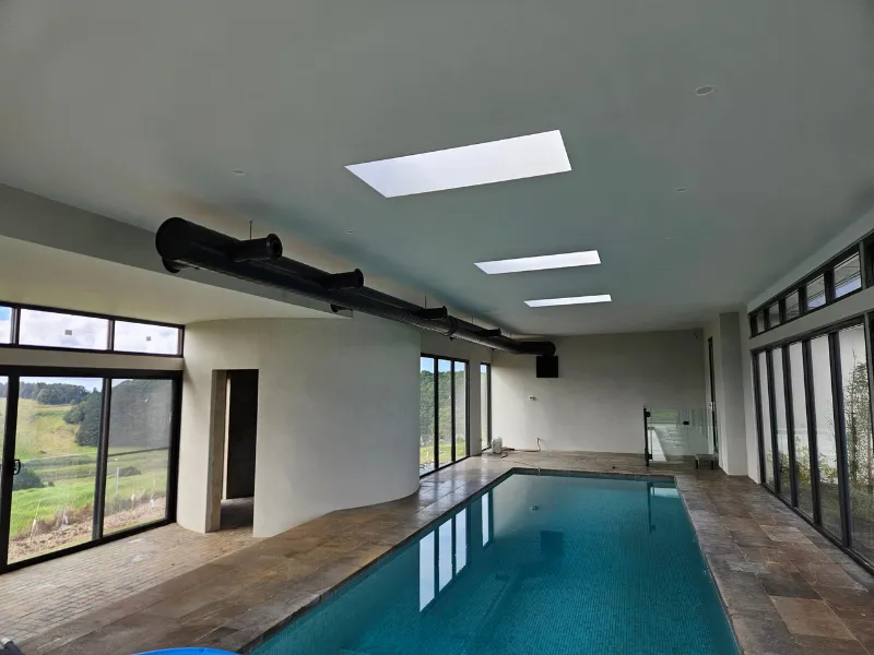 Indoor pool hall with an exposed black spiral duct where concealed ductwork was not possible