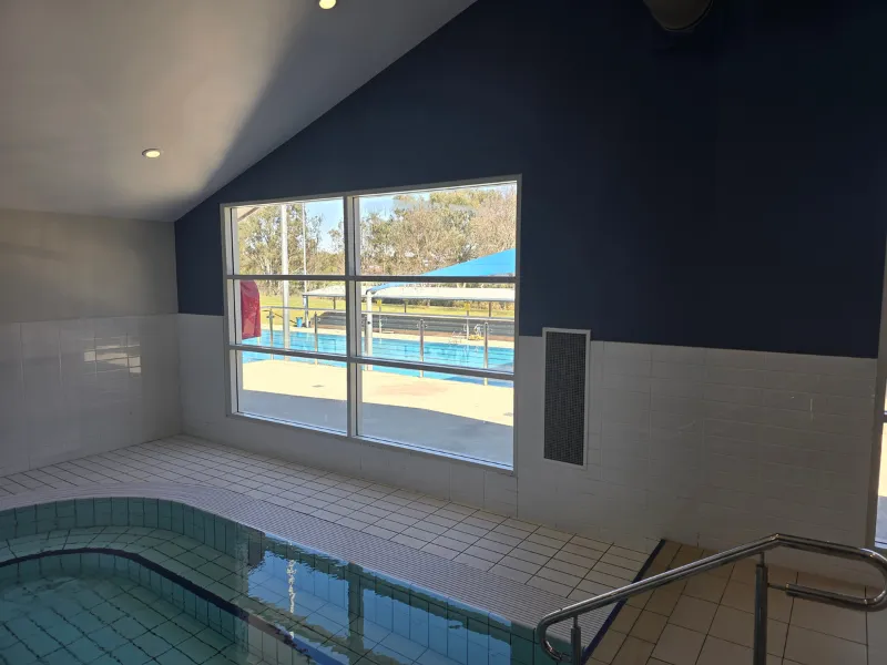 Indoor spa room with a large window overlooking an outdoor pool